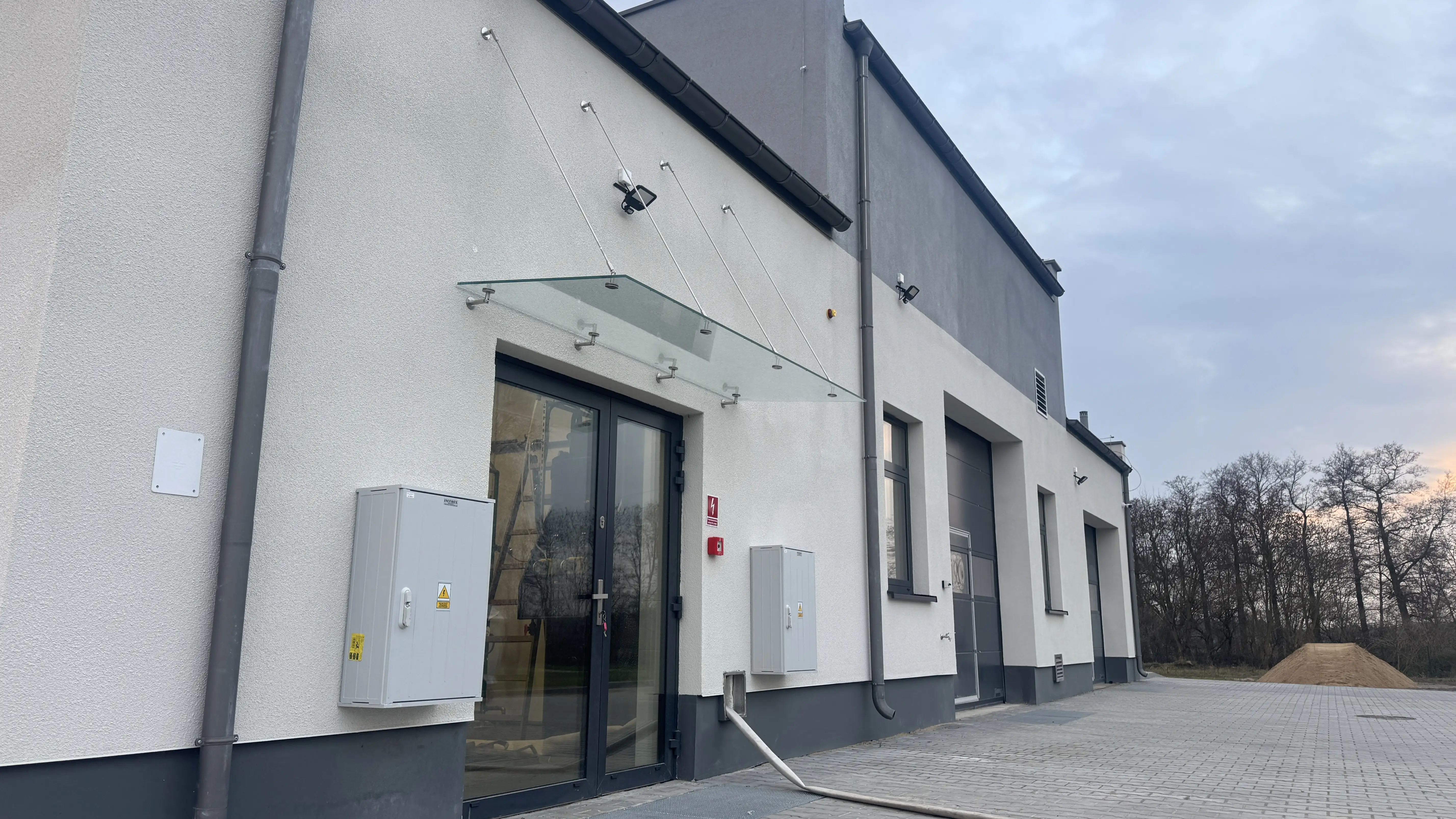 Drzwi aluminiowe ze szklanym daszkiem nad wejściem do hali — realizacja Płock